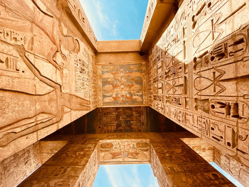 Hieroglyphs carved into the walls of Medinet Habu under a blue sky