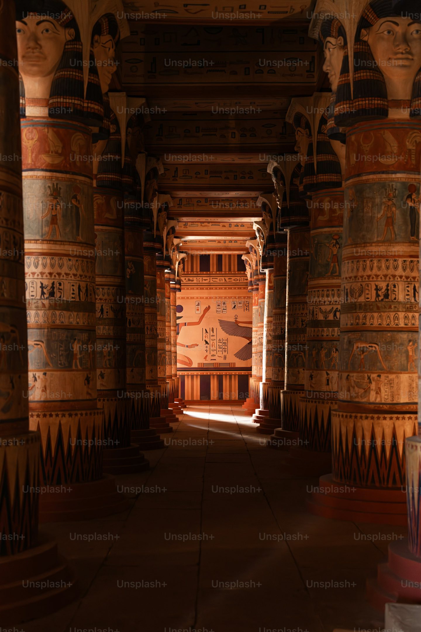 Painted columns lining a temple hall towards a sunlit doorway